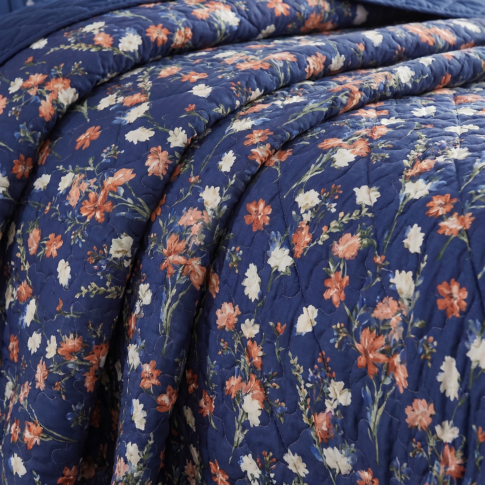 Floral quilt with blue background featuring pink, orange, and white flowers.